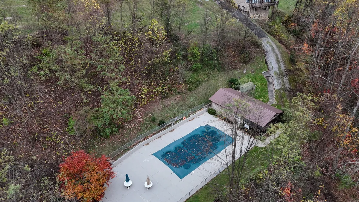 A serene, resort-style swimming pool is nestled amidst colorful autumn trees, providing a refreshing space for relaxation and leisure. The surrounding nature creates a tranquil, secluded environment perfect for unwinding after a day of adventure.
