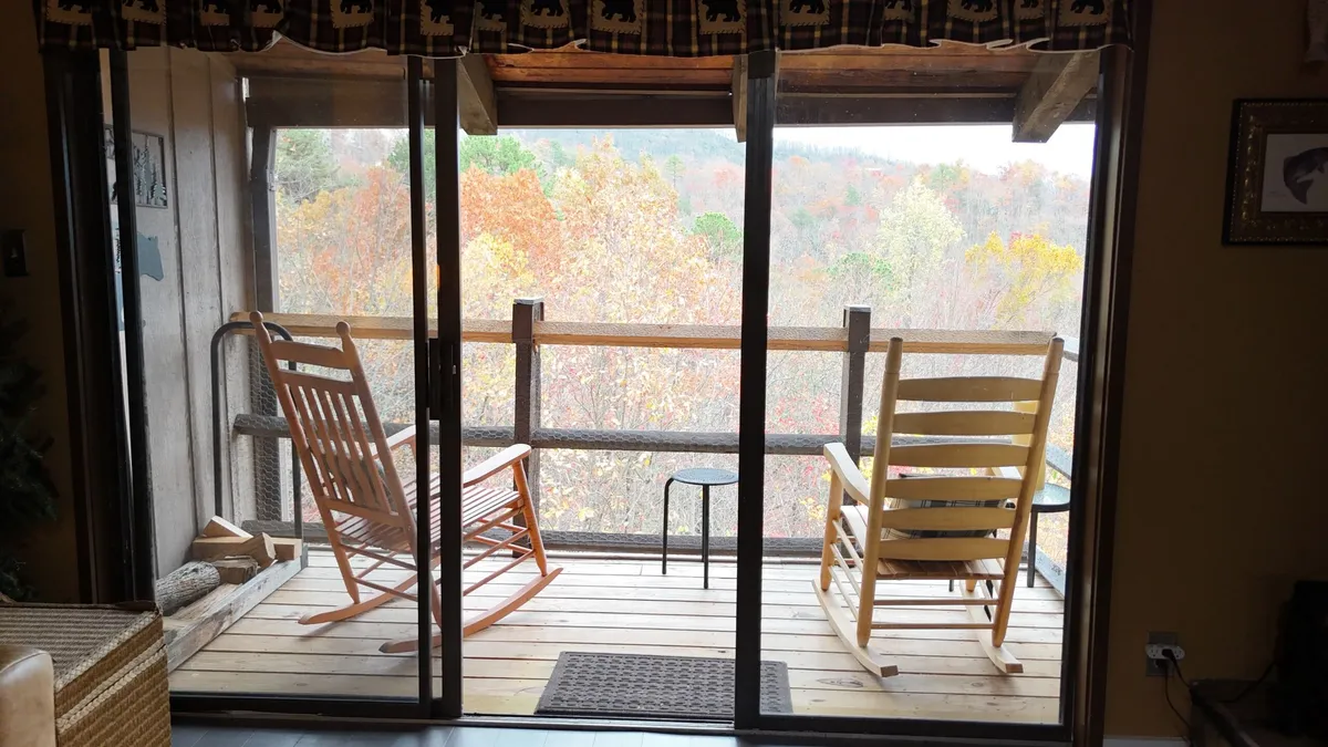 This image features a wooden deck with classic rocking chairs overlooking vivid autumn foliage. The setting is peaceful, ideal for relaxing after a day of mountain adventures, and suggests moments spent sipping coffee or watching the sunset enveloped in nature.