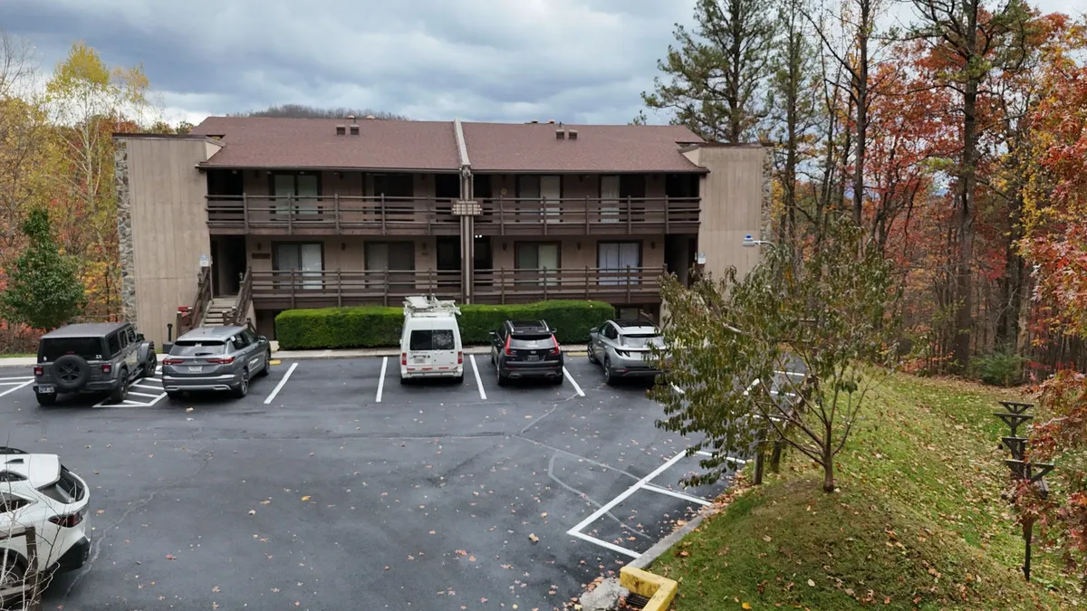 This image showcases a two-story building surrounded by trees with a calm, welcoming atmosphere. The parking lot hints at easy access for families, while the natural setting suggests a peaceful environment perfect for relaxing after a day of adventure.